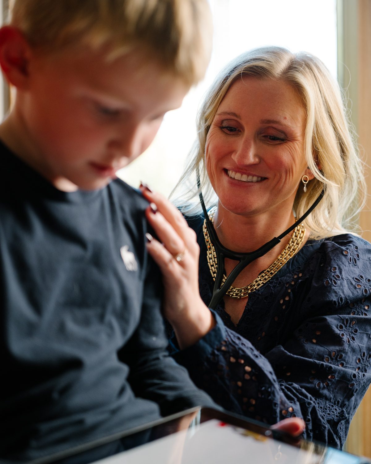 Nurse practitioner listening to the heart of a young by with a stethoscope